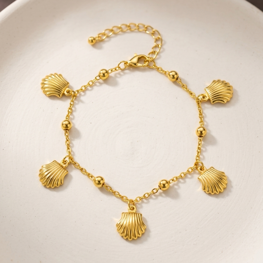 18kt gold plated chain bracelet with five dangling scallop shell charms on white surface.