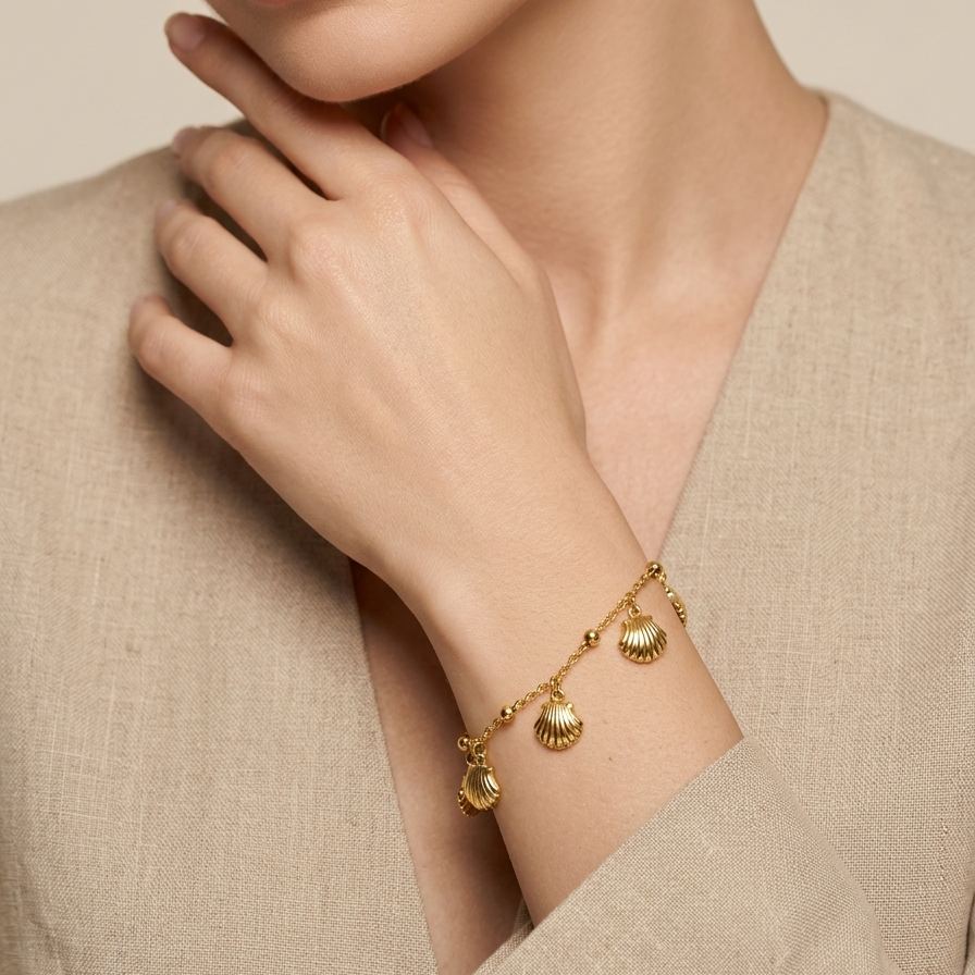 Woman wearing a 18kt gold plated bracelet with small charms against a neutral background.