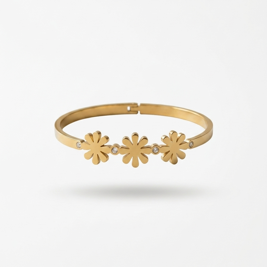 18k gold plated minimalist bangle bracelet featuring three solid gold daisy motifs and tiny crystal accents, resting on a white plate.