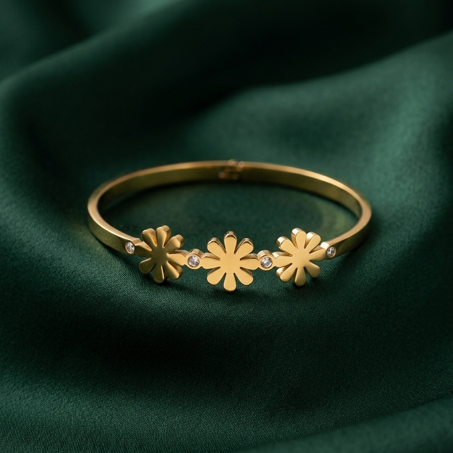 18k gold plated minimalist bangle bracelet featuring three solid gold daisy motifs and tiny crystal accents, resting on a white plate.