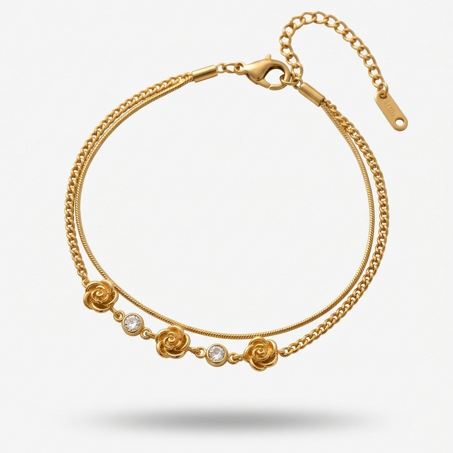 18k gold plated double chain bracelet featuring sculpted rose charms and crystal accents, resting on a matte white surface.