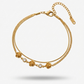 18k gold plated double chain bracelet featuring sculpted rose charms and crystal accents, resting on a matte white surface.