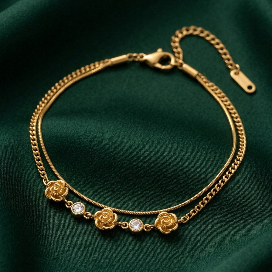 18k gold plated double chain bracelet featuring sculpted rose charms and crystal accents, resting on a matte white surface.