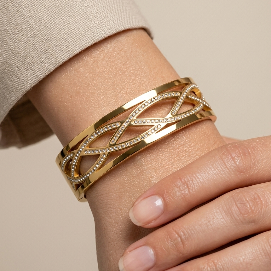 Wide 18k gold plated statement bangle bracelet featuring a criss-cross cutout pattern lined with sparkling pave CZ diamonds on a wrist with a neutral background