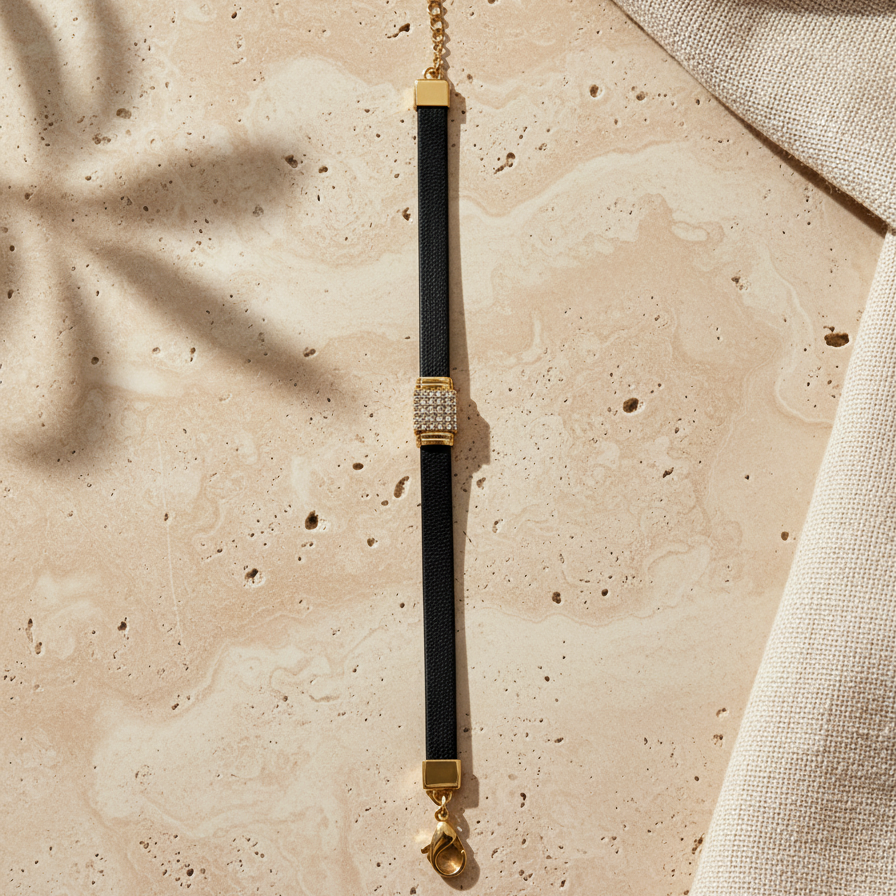 sporty black ribbed bracelet featuring a bold, rectangular 18k gold plated clasp covered in pave CZ diamonds on a beige stone surface