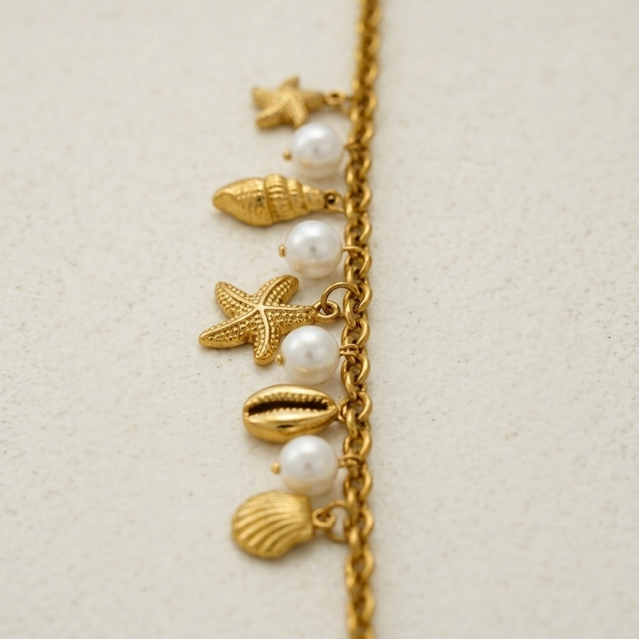 18k gold plated chain bracelet adorned with dangling charms including golden starfish, seashells, and white pearls.