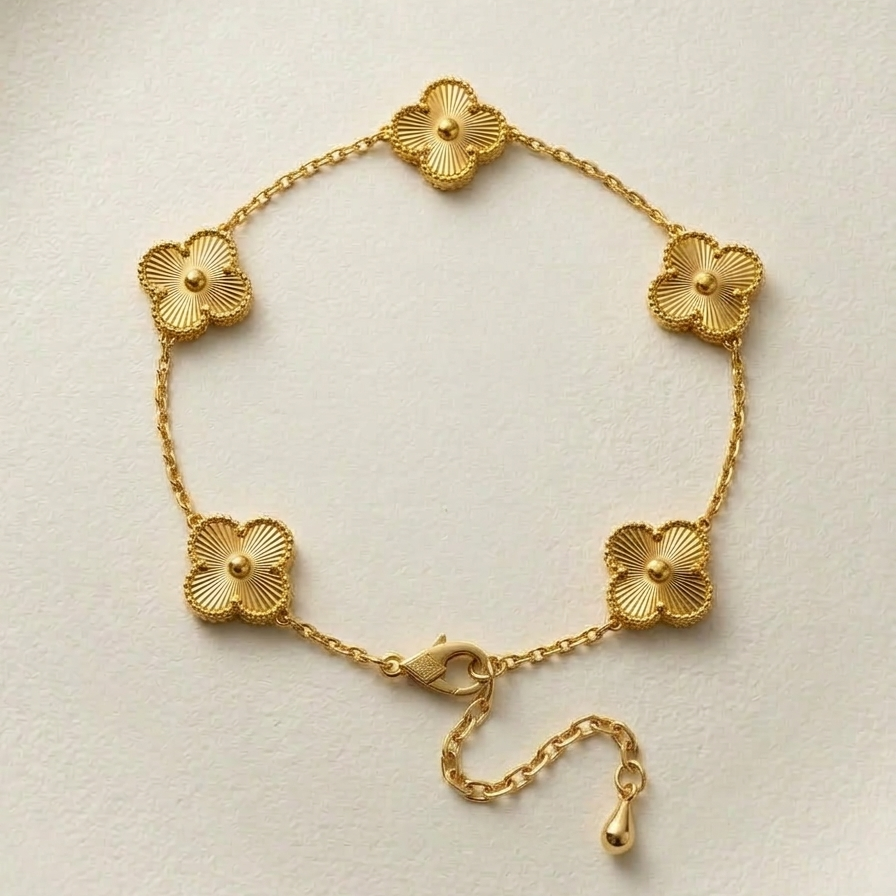 18k gold plated delicate chain bracelet featuring five textured four-leaf clover motifs, resting vertically on a matte white surface.