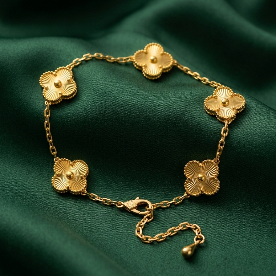 18k gold plated delicate chain bracelet featuring five textured four-leaf clover motifs, resting vertically on a matte white surface.