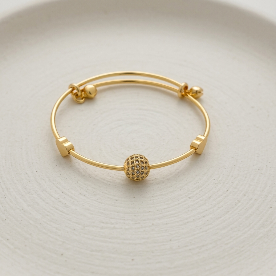 18k gold plated adjustable sliding bangle bracelet featuring a central sphere covered in pave CZ diamonds and two small gold heart accents.