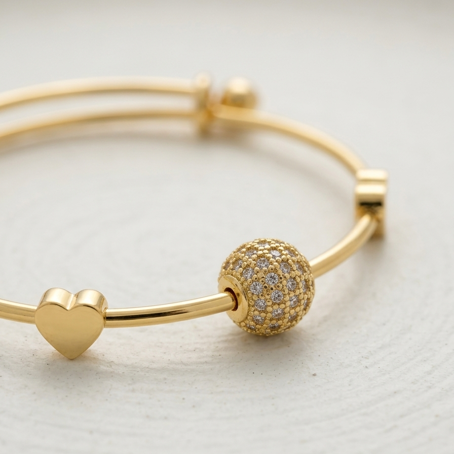 18k gold plated adjustable sliding bangle bracelet featuring a central sphere covered in pave CZ diamonds and two small gold heart accents.