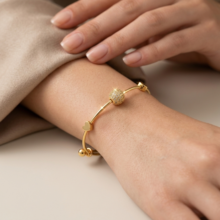 18k gold plated adjustable sliding bangle bracelet featuring a central sphere covered in pave CZ diamonds and two small gold heart accents.