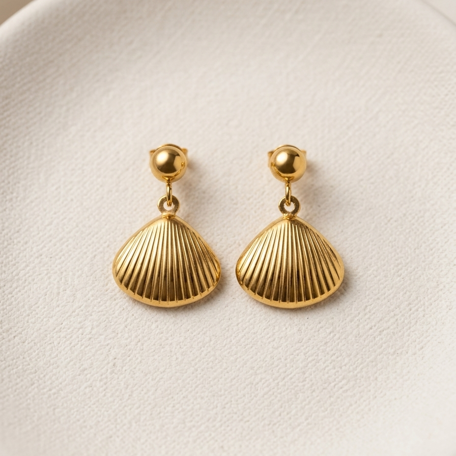 18kt gold plated shell drop earrings with scallop charm on white plate.