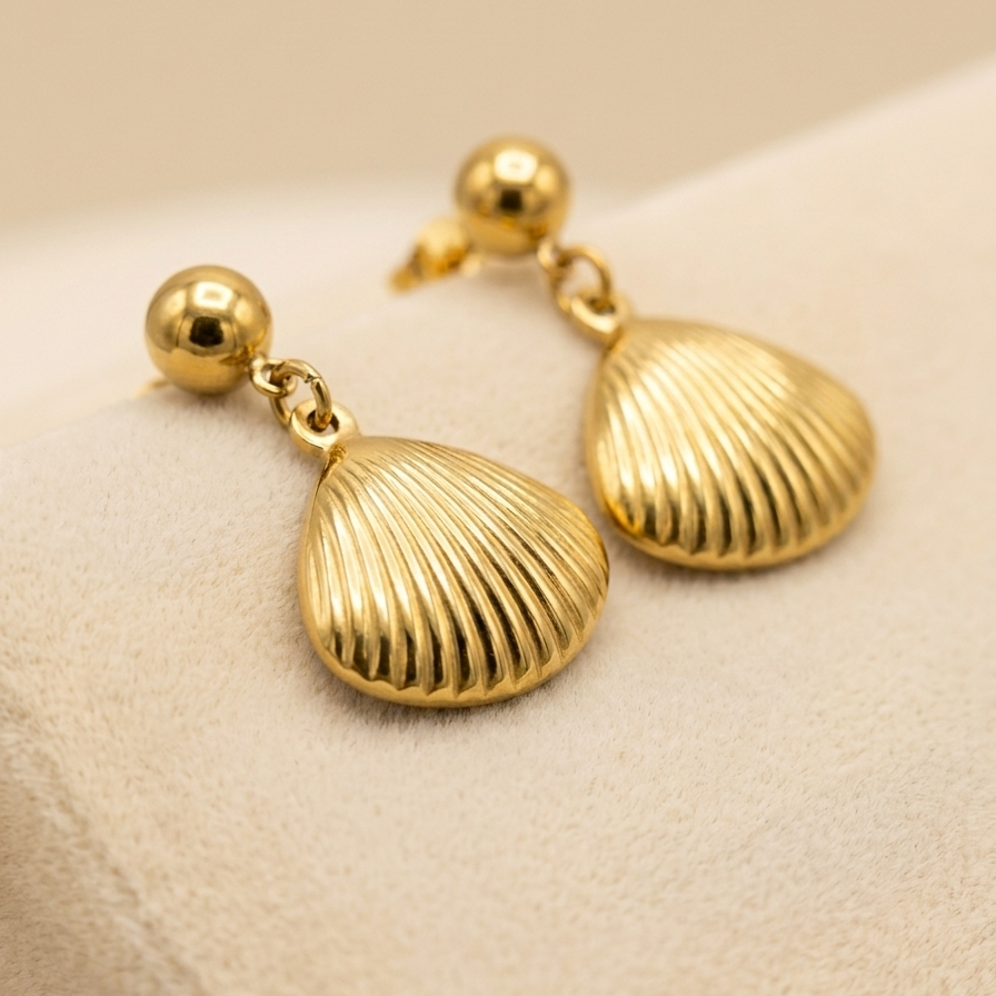 18kt gold plated shell drop earrings on a beige background.