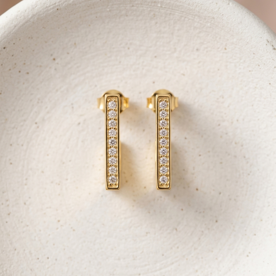 18kt gold plated geometric hoops with diamond accents on a textured white surface.