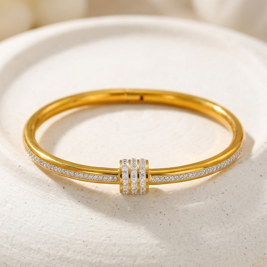 18kt gold plated roller bangle with diamond accents on a white stone surface.