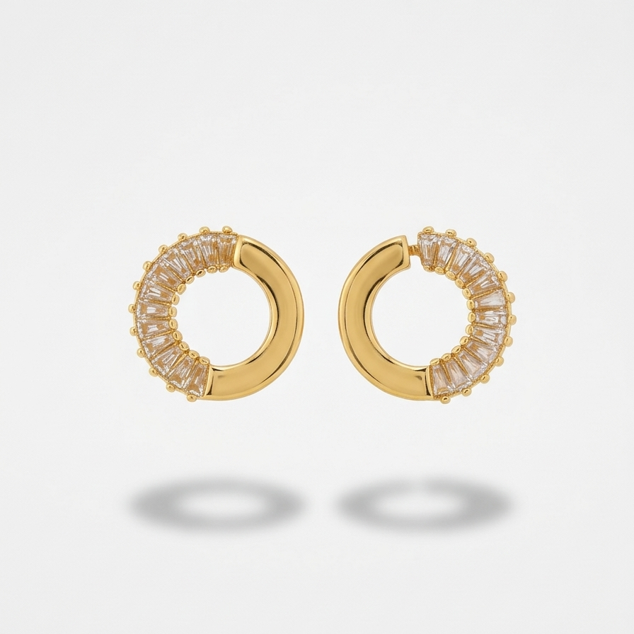 Gold hoop earrings with clear gemstones on a light gray background