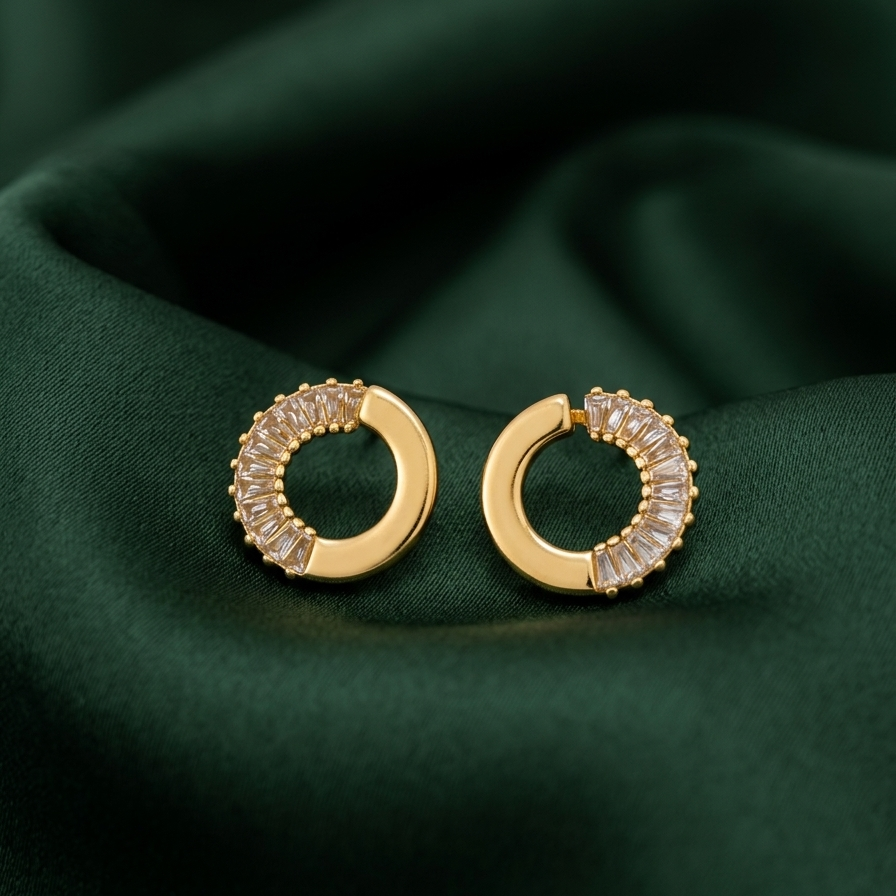 Gold hoop earrings with gemstones on a green fabric background