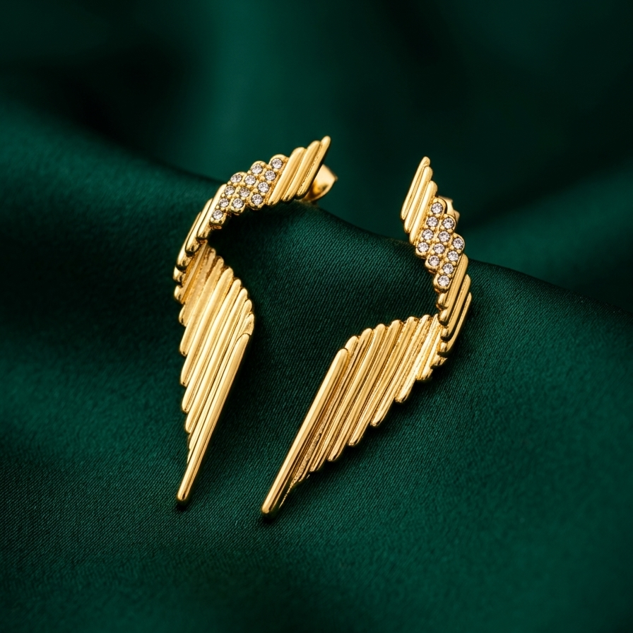 Pair of large 18k gold plated statement drop earrings with a ribbed wing texture and CZ diamond accents at the top on a green silk fabric
