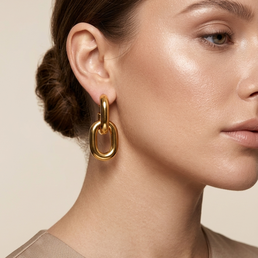 Pair of 18k gold plated drop earrings featuring two thick, interlocking oval chain links worn by a model against a neutral background