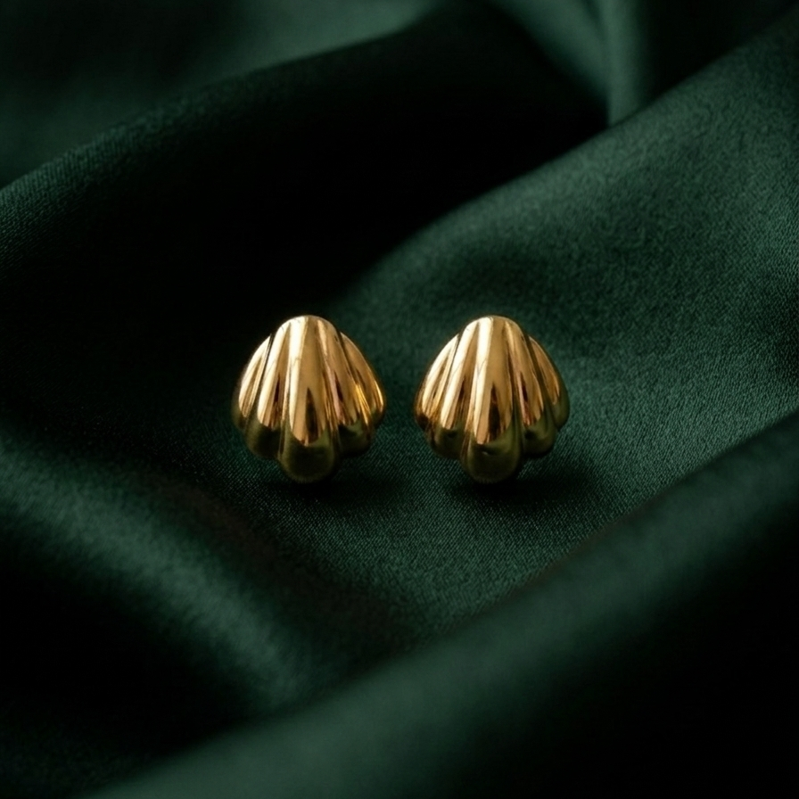 18k gold plated stud earrings shaped like polished minimalist scallop seashells, resting on green silk fabric.