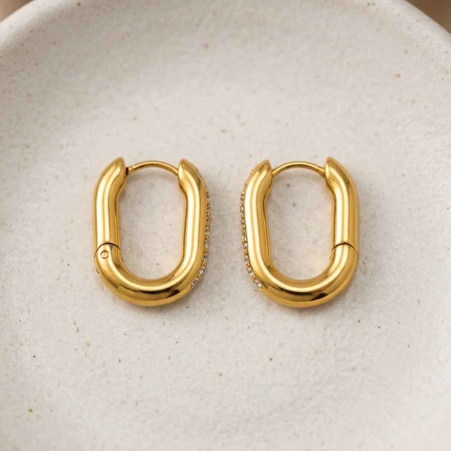 Pair of 18k gold plated oval Huggies hoop earrings featuring a center row of sparkling CZ diamonds.