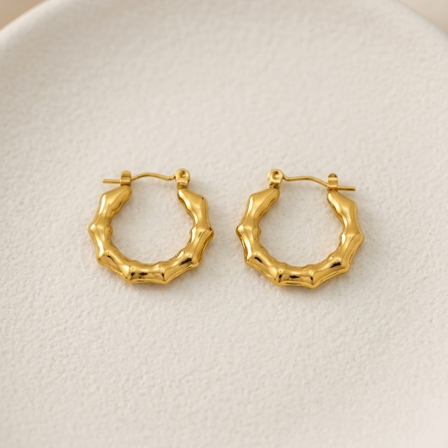 Pair of 18k gold plated mini hoop huggie earrings featuring a sculpted, textured bamboo design.
