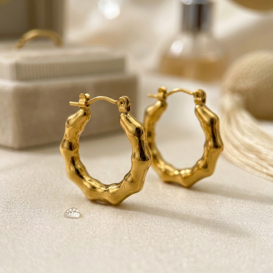 close up of a Pair of 18k gold plated mini hoop huggie earrings featuring a sculpted, textured bamboo design.