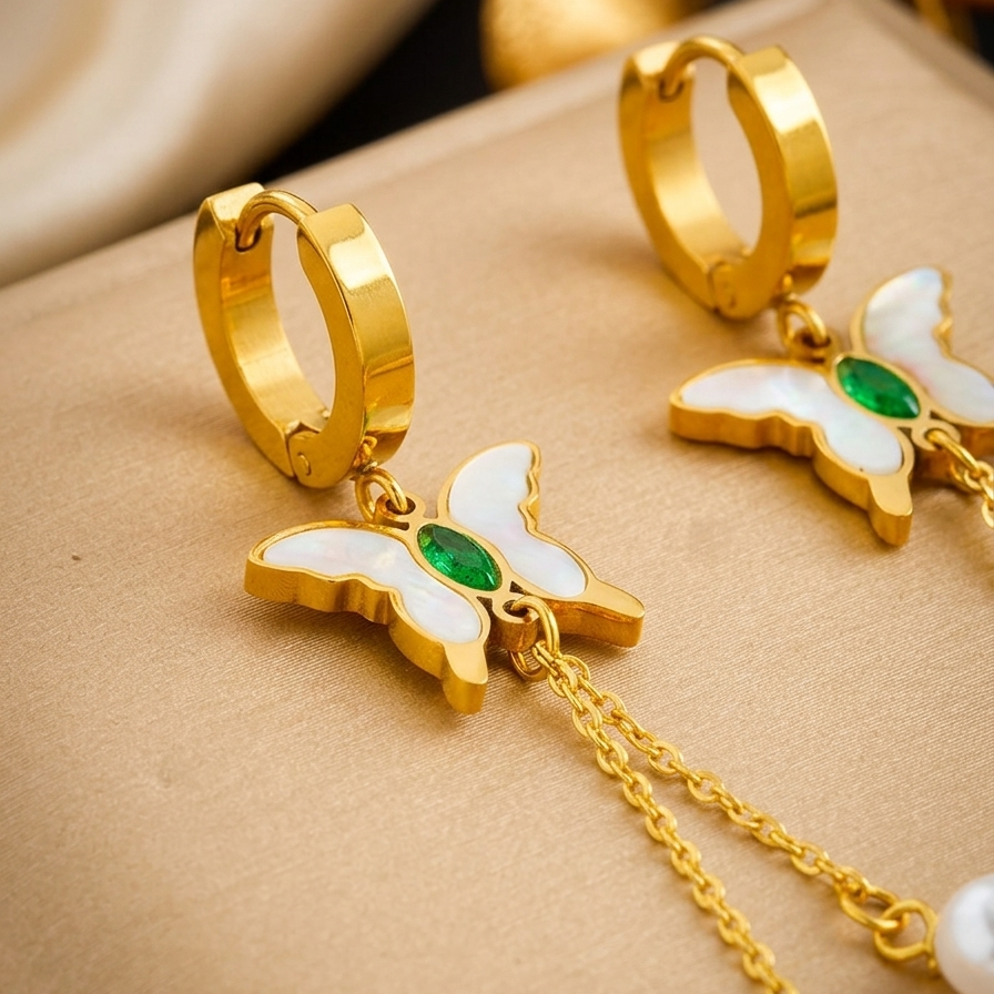 18kt gold plated butterfly pearl drops earrings with green and white accents on a beige surface
