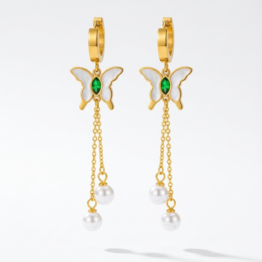 Butterfly-shaped earrings with gold frames, green gemstones, and pearl drops floating on a white background.