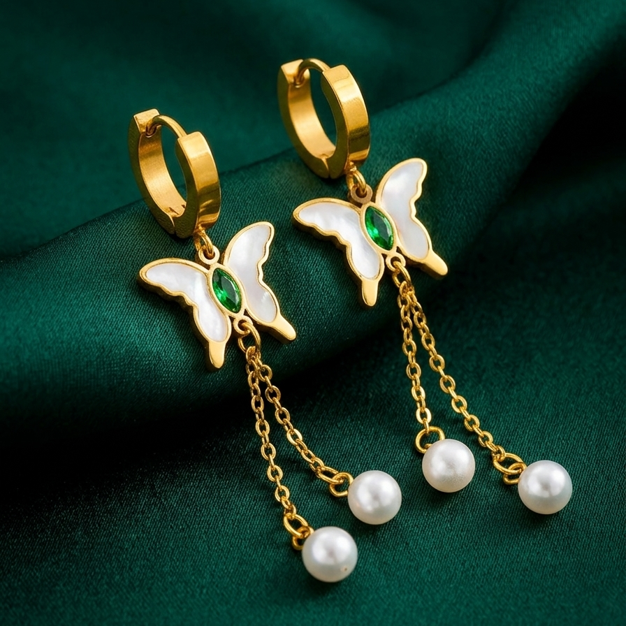 18kt gold plated butterfly earrings with pearl chains on a green fabric background.