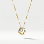 Gold necklace with double interlocking open heart pendant on beige plate.