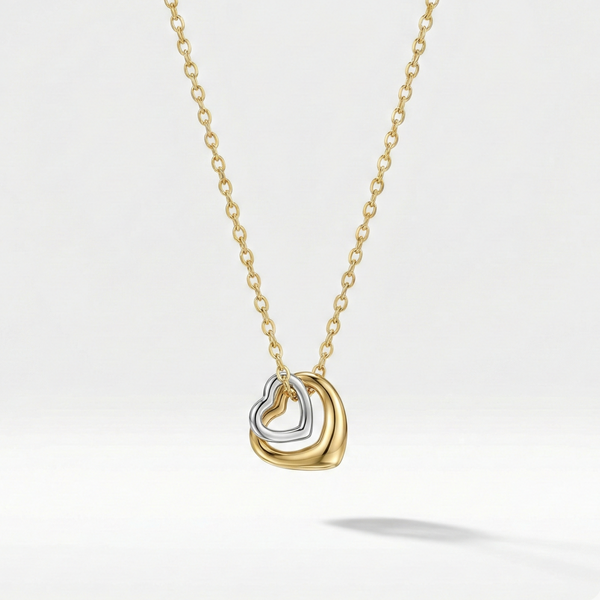 Gold necklace with double interlocking open heart pendant on beige plate.