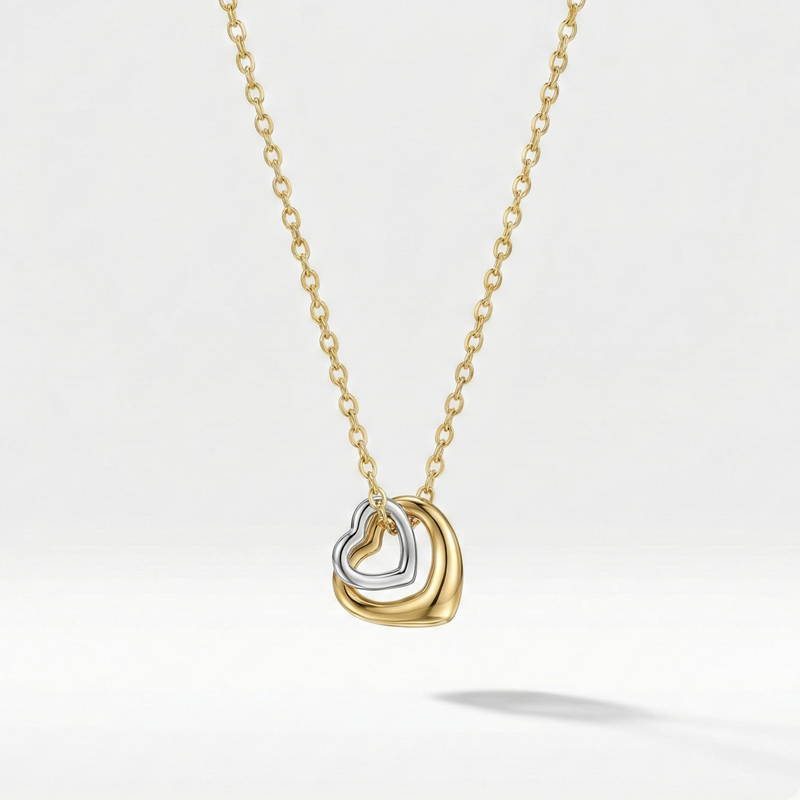 Gold necklace with double interlocking open heart pendant on beige plate.