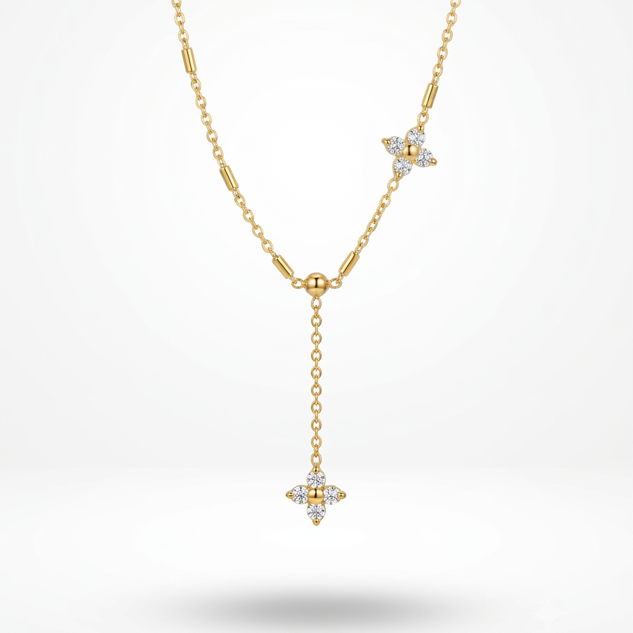 A delicate yellow gold Y-necklace featuring a main chain with a small gold bead, a star-shaped crystal accent, and a longer drop chain ending in a matching crystal star pendant, shown against a light gray gradient background.