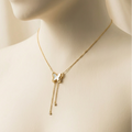 Gold butterfly necklace with dangling tassels and white inlay on packaging card.