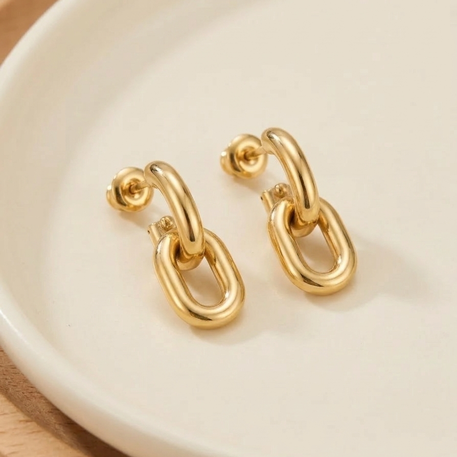 Pair of 18k gold plated drop earrings featuring two thick, interlocking oval chain links on marble surface