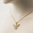 Gold dove pendant necklace with crystal zirconia wings in beige jewelry box packaging.