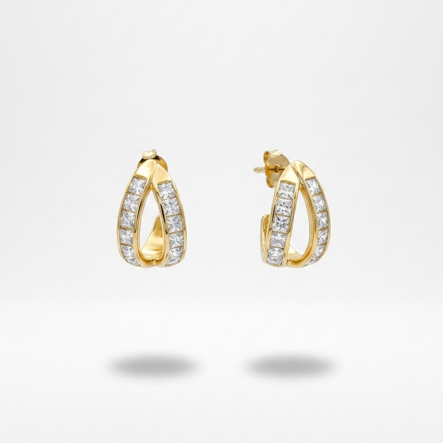 A pair of gold huggie hoop earrings adorned with pavé-set clear stones, shown against a clean white background with soft shadows below.