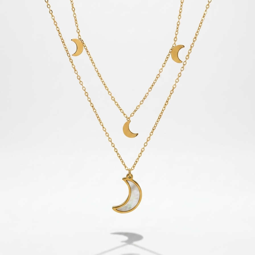 A double-layered gold necklace set featuring crescent moon charms, with one larger gold crescent pendant filled with a white inlay and one smaller gold crescent pendant on the chain, displayed against a clean white background.