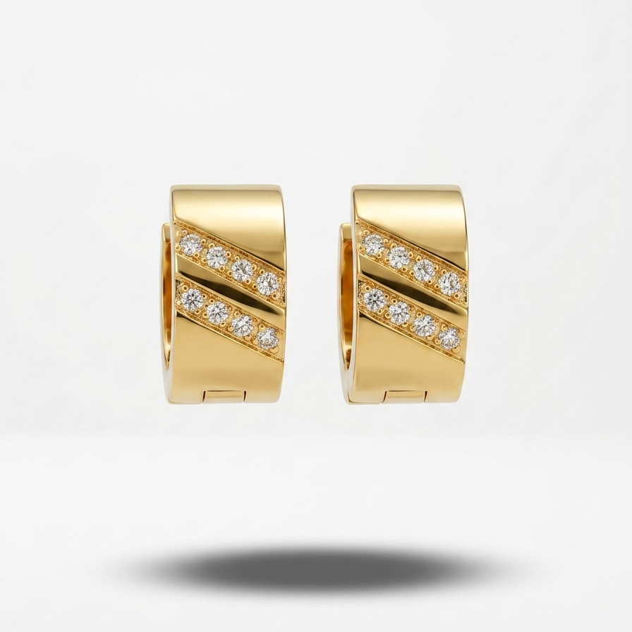 A pair of gold huggie hoop earrings with diagonal bands of pavé-set clear stones, shown against a clean white background with a soft shadow below.