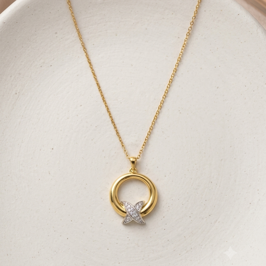 A delicate gold chain necklace with a minimalist pendant featuring a gold ring and a small silver-toned star embellished with clear stones, displayed on a textured white ceramic dish.