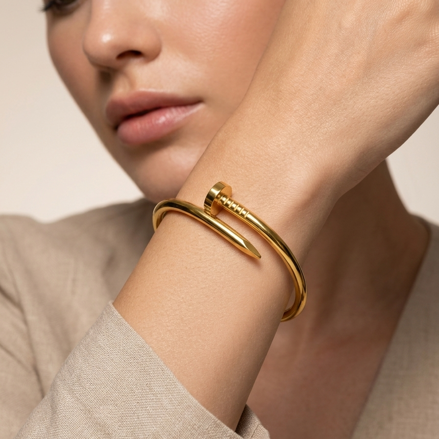Woman wearing a 18kt gold plated nail cuff bracelet on a neutral background.