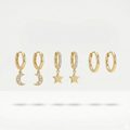 Set of gold huggie earrings with dangling star and moon charms on packaging card.