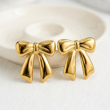 Large 18kt gold plated ribbon bow studs on white background.