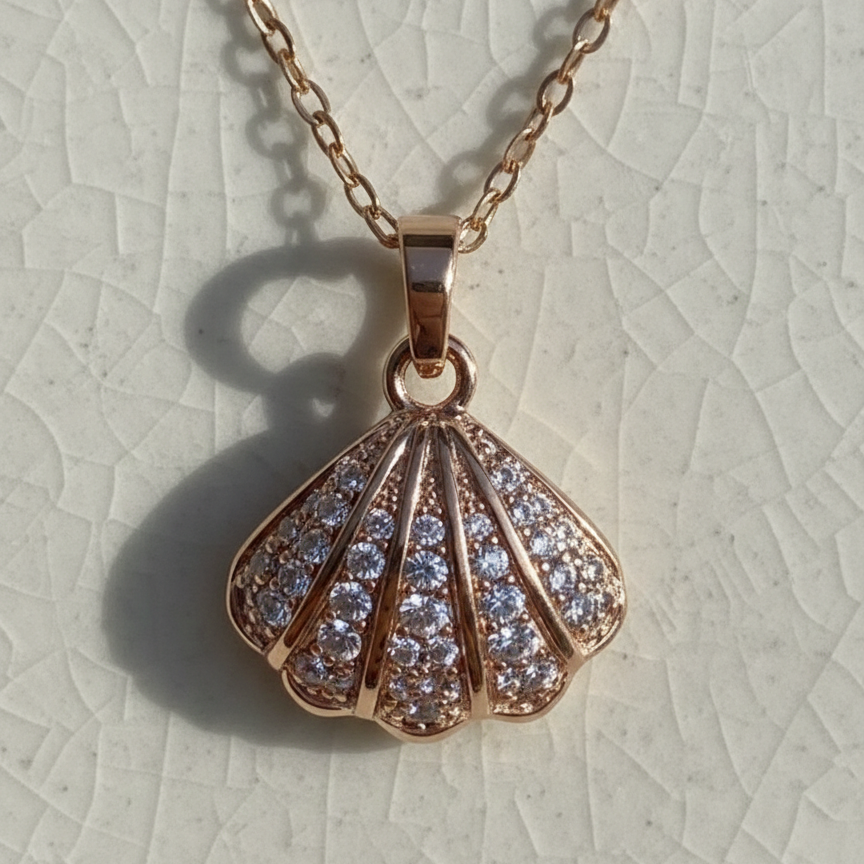 Rose gold shell-shaped pendant necklace on a light gray textured background