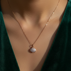 Necklace with a shell pendant worn by a person in a green outfit