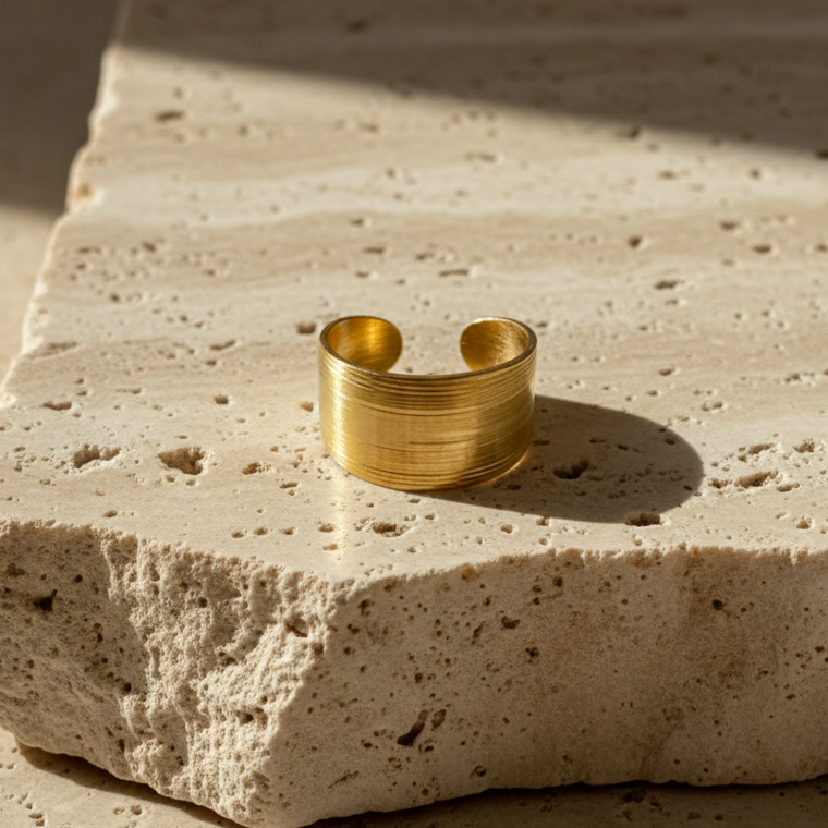 Wide gold ring with geometric basket weave texture standing on white surface.