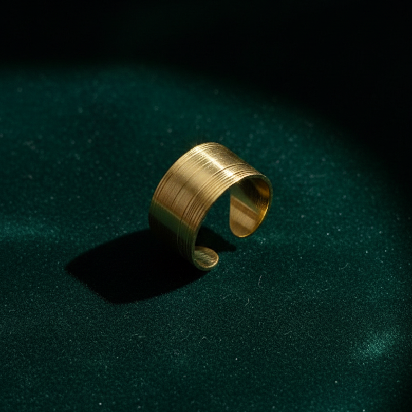 Wide gold ring with geometric basket weave texture standing on white surface.