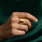 Wide gold ring with geometric basket weave texture standing on white surface.