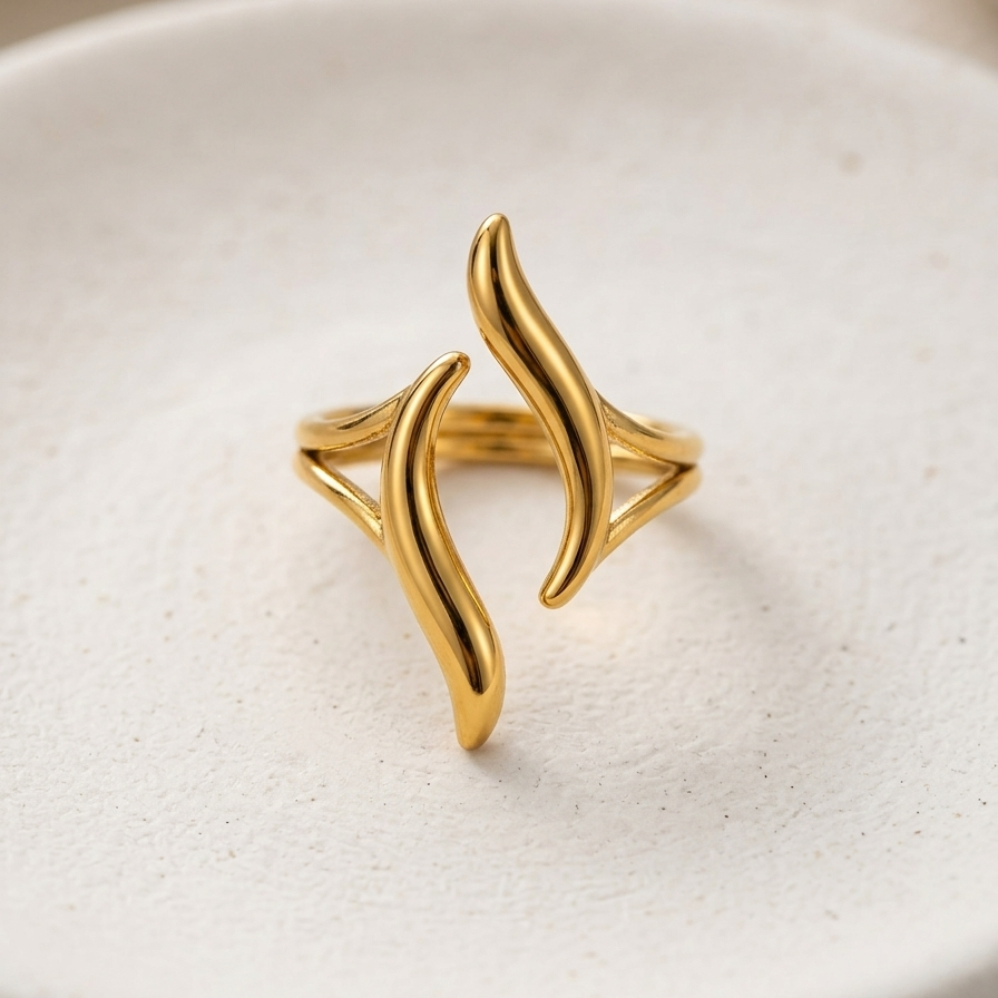 18kt gold plated ring with a wavy design on a beige surface